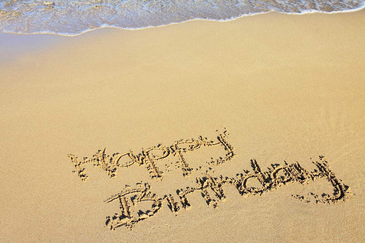 happy birthday inscrit dans le sable sur la plage