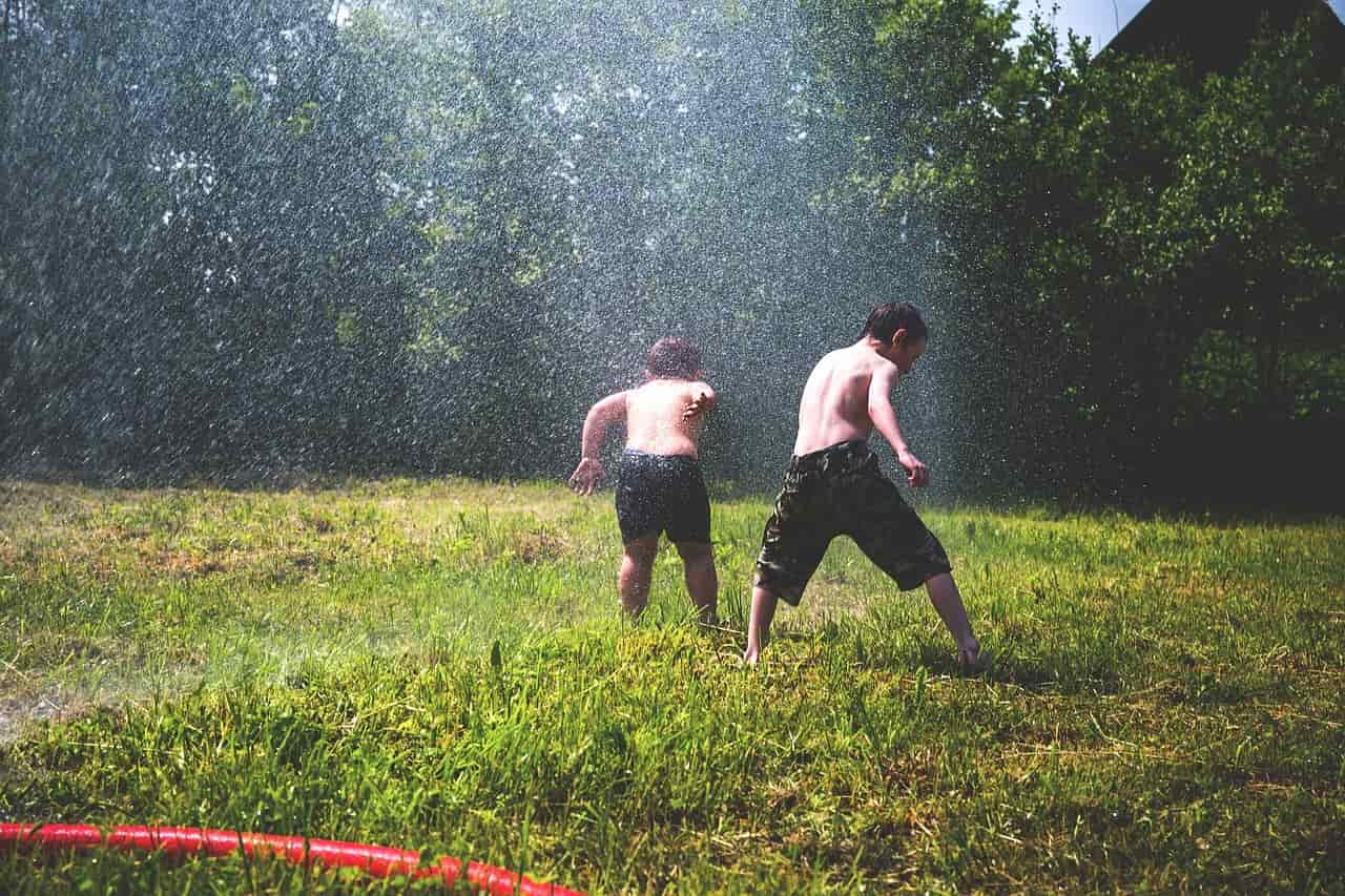 enfants jouant sous un jet d'eau été